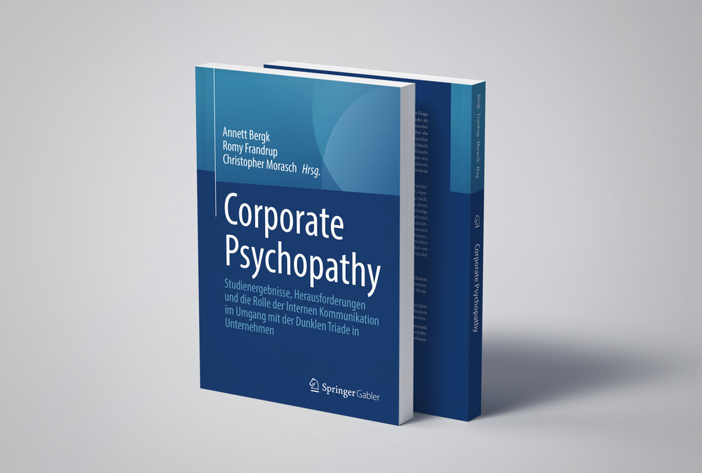 Zwei Bücher mit der Aufschrift "Corporate Psychopathy" stehen auf einem hellgrauen Untergrund und werfen einen Schatten.